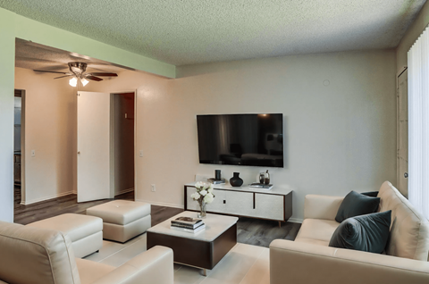 a living room with white couches and a tv on the wall